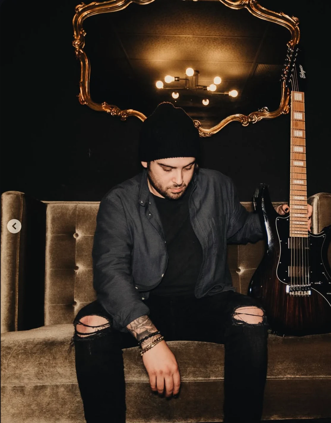 Gino Sgambelluri seated beside a guitar